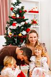 Parents with two daughters spending time near Christmas tree