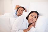 Woman lying awake next to her sleeping boyfriend