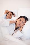 Woman covering her ears to block her boyfriends snoring