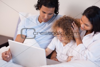 Family with laptop sitting on the bed