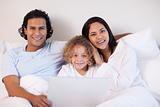 Family sitting on the bed with notebook