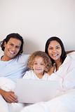 Family sitting on the bed with notebook together
