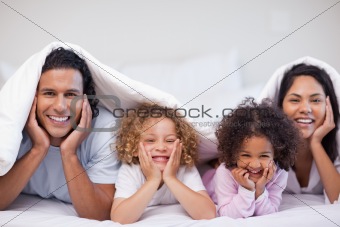 Happy family hiding under the blanket