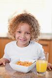 Happy girl having cereals and orange juice for breakfast