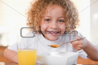 Smiling girl having breakfast in the kitchen
