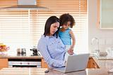 Mother and daughter using laptop in the kitchen together