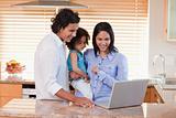 Family using laptop in the kitchen together