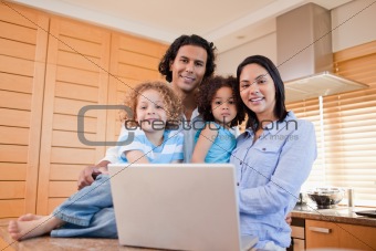 Happy family with laptop standing in the kitchen together