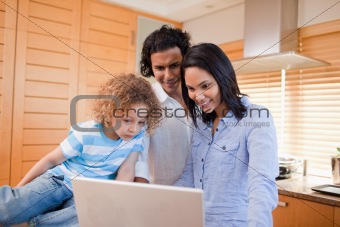 Happy family surfing the internet in the kitchen together