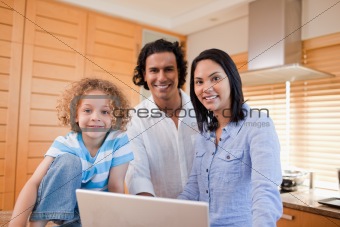 Joyful family surfing the internet in the kitchen together