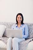 Smiling woman on the sofa surfing the internet