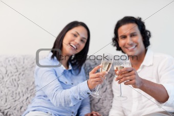 Couple celebrating with sparkling wine on the couch