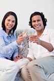 Happy couple drinking sparkling wine on the sofa