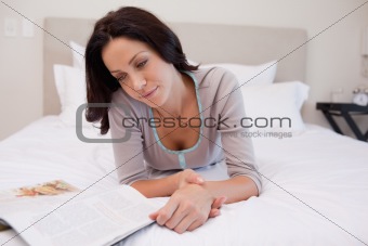 Woman laying on the bed reading a magazine