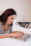 Woman working on the laptop in the bedroom