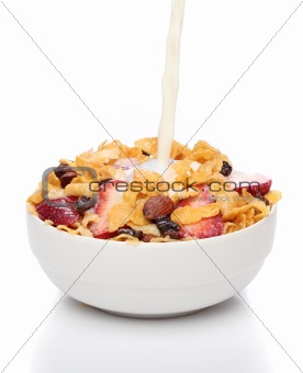 Pouring milk into a bowl of cornflakes and fruits