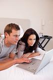 Couple using laptop in the bedroom together