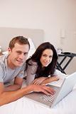 Smiling couple using laptop in the bedroom together