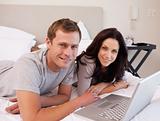 Happy couple using laptop on the bed together