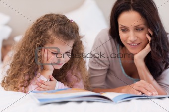 Little girl reading bedtime story with her mother