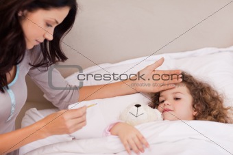 Mother measuring her daughters temperature