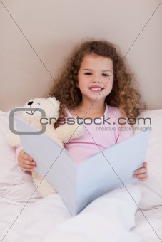 Girl sitting on the bed with a book