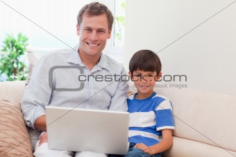 Father and son with laptop on the sofa