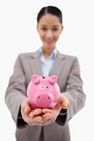 Portrait of a happy businesswoman showing a piggy bank