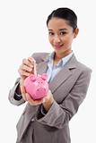 Portrait of a businesswoman putting a bank note in a piggy bank