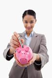 Portrait of a young businesswoman putting a bank note in a piggy bank