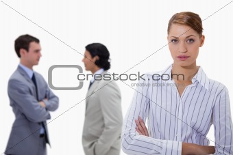 Businesswoman with talking colleagues behind her