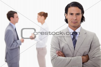 Serious businessman with talking colleagues behind him