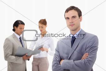 Young businessman with talking colleagues behind him
