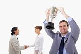 Businessman raising cup with hand shaking colleagues behind him