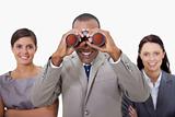 Smiling businessman with colleagues looking through binoculars