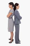 Businesswomen with arms folded standing back on back