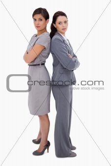 Serious businesswomen standing back on back