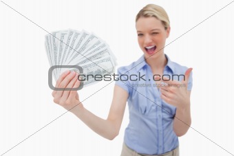 Woman holding money and pointing at it