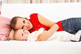 Smiling mother with baby laying on couch