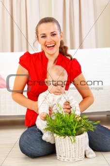 Smiling mommy showing plant to her baby