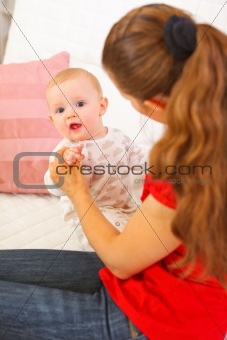 Interested baby playing with mothers on couch