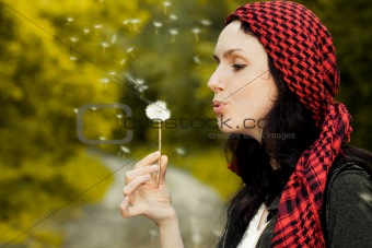 Girl blowing on dandelion 
