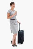 Side view of woman with coffee and wheely bag
