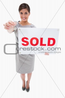 Real estate agent with sold sign handing over key