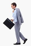Side view of walking and smiling businessman with suitcase