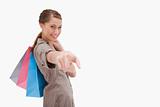 Side view of smiling woman pointing with shopping bags