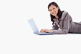 Side view of smiling woman lying while working on laptop