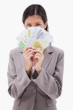 Businesswoman hiding face behind money