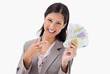 Smiling businesswoman pointing at her money