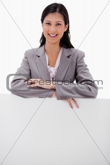 Smiling young businesswoman leaning on blank wall